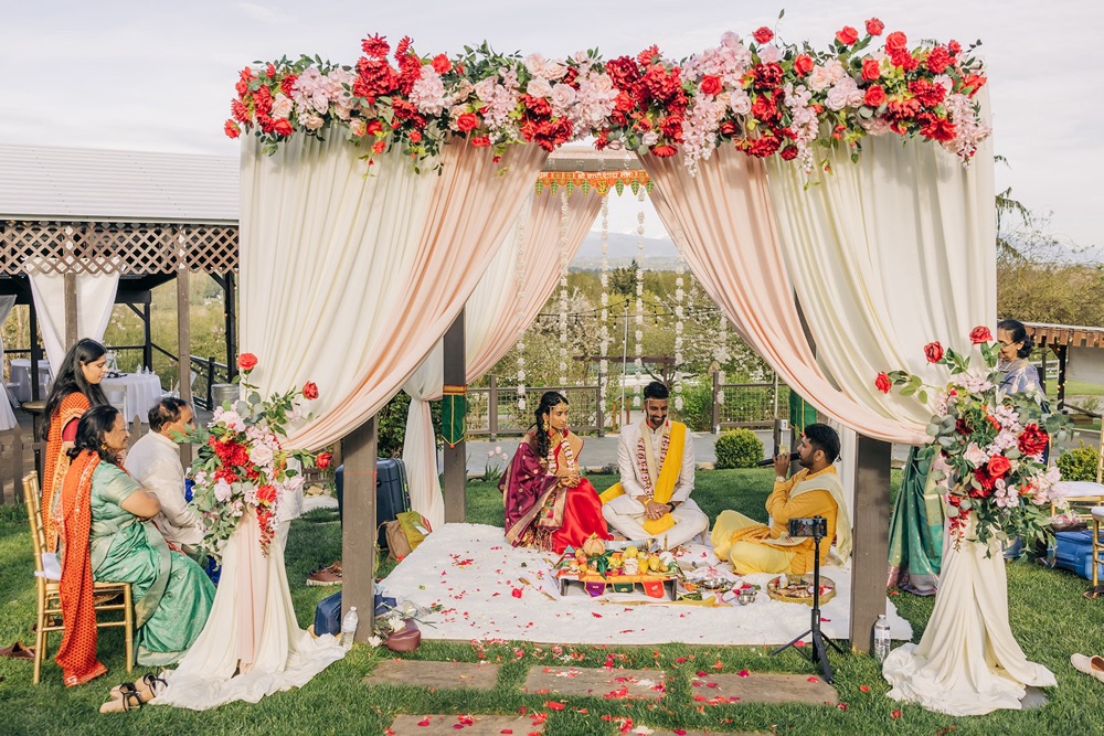Hindu wedding ceremony underway beneath a floral Mandap on the lawn at Eagle Mountain Venue in Arlington