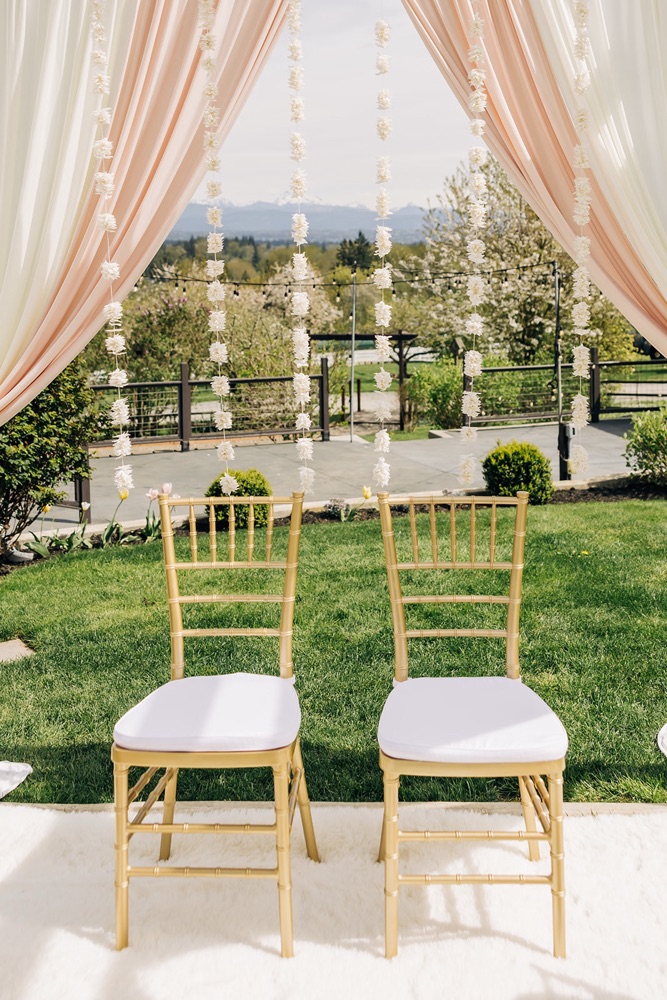 Gold Mandap seating on a white floor covering, framed by blush drapery and jasmine garlands, at Eagle Mountain Venue