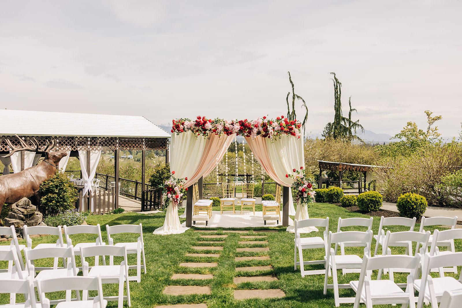Mandap ceremony aisle view with white guest seating and floral canopy at an outdoor venue in the greater Seattle area