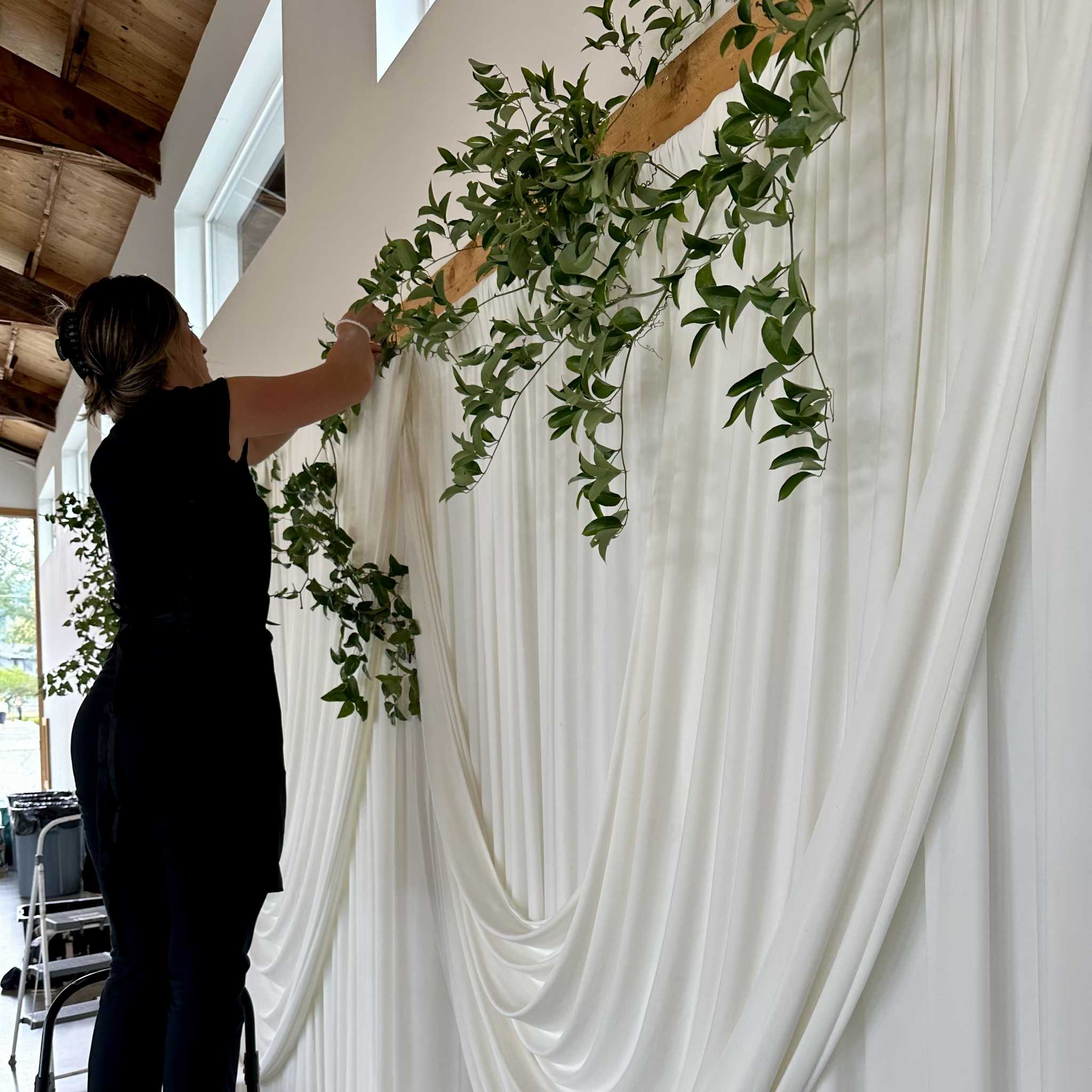 Maquel Bradbury, Lead Designer of Bradbury Events, installing white fabric drapery at a South Asian ceremony venue in the Seattle area -- a glimpse into our story